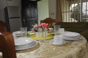 a dining room table with plates and flowers on it at Cabañas Brisas Alto Boquete in Boquete