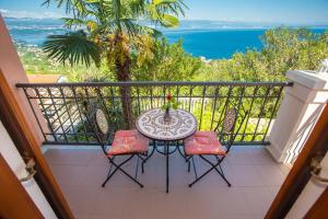 a balcony with a table and chairs and the ocean at Apartments Jasminka Lovran in Lovran