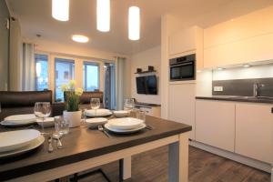 cocina y sala de estar con mesa y copas de vino en Wohnen am Yachthafen W25, en Cuxhaven