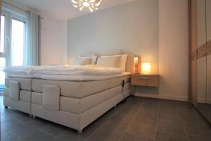 ein Schlafzimmer mit einem weißen Bett in einem Zimmer in der Unterkunft Wohnen am Yachthafen W25 in Cuxhaven