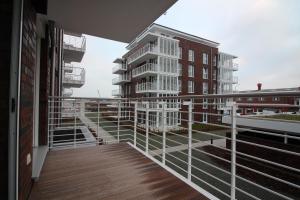 a balcony with a white railing and some buildings at Wohnen am Yachthafen W25 in Cuxhaven