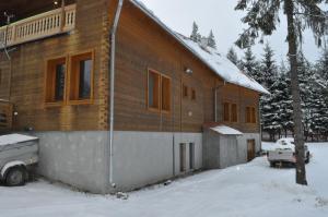 Sîntimbru-Băi的住宿－Mofetta Panzió，雪中的房子,前面有一辆卡车