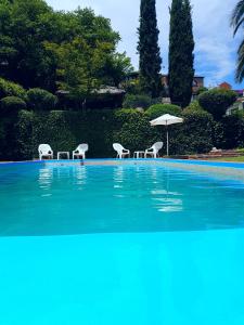 a swimming pool with chairs and an umbrella at Vistas Apart in Embalse