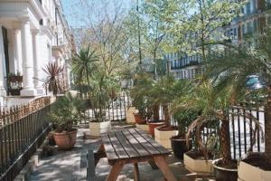a wooden picnic table in a courtyard with plants at Oliver Hotel in London