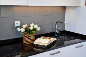 a kitchen counter with a vase of flowers and a book at Confluentia H&A - Believe It or Not Apartments in Coimbra