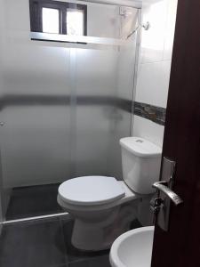 La salle de bains blanche est pourvue de toilettes et d'un lavabo. dans l'établissement Los Cardenales, à Santa Ana