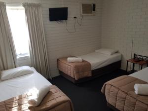 
a bed room with two beds and a desk at Centrepoint Motor Inn in Rockhampton
