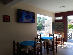 Hostería Boutique El Puente Adults Only في ميرلو: غرفة طعام مع طاولات وتلفزيون على الحائط