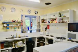 a kitchen with white cabinets and clocks on the wall at Apollo Bay Backpackers in Apollo Bay
