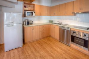 a kitchen with a white refrigerator and wooden cabinets at Drovers Rest in Dinner Plain