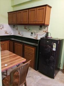 a kitchen with a black refrigerator and wooden cabinets at shirley's guest house in Majorda