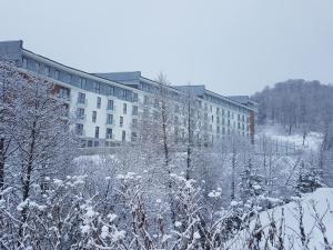 un bâtiment recouvert de neige devant un bâtiment dans l'établissement Dima Orbi apart. Bakuriani, à Bakuriani