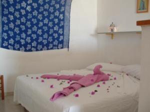 a white bed with pink sheets and flowers on it at La Salina in Lampedusa
