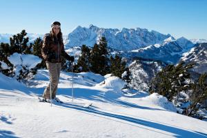 une femme debout à skis sur une montagne enneigée dans l'établissement Hotel Garni Tirol, à Walchsee