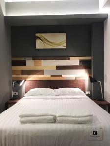 um quarto com uma grande cama branca e uma parede preta em Campagne Hotel and Residence - SHA Plus em Pathum Thani