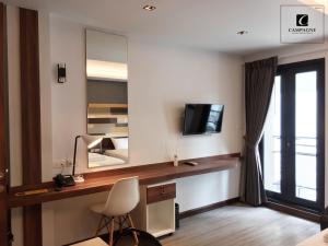 a bedroom with a desk with a television and a mirror at Campagne Hotel and Residence - SHA Plus in Pathum Thani