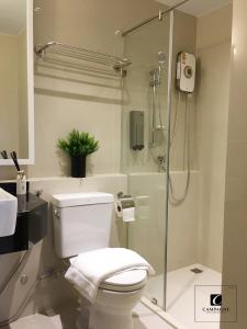 a bathroom with a toilet and a glass shower at Campagne Hotel and Residence - SHA Plus in Pathum Thani