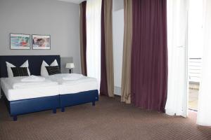 a bedroom with a blue and white bed and curtains at Hotel Arena Inn - Berlin Mitte in Berlin