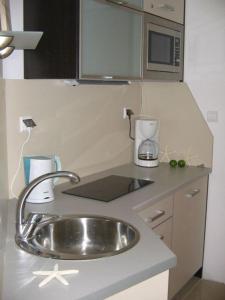 eine Küchentheke mit einer Spüle und einer Mikrowelle in der Unterkunft Apartament Rezydencja Bursztyn in Świnoujście