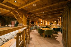 un restaurante con techos de madera, mesas y sillas en Hotel Xalet Montana, en Soldeu