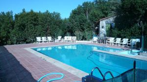 a swimming pool with white chairs and a table and chairs at La Maison de Vérotte in Claira