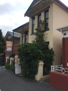 a building with a bush in front of it at Narrara Backpackers Hobart in Hobart