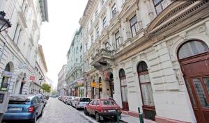 a row of cars parked on a city street next to buildings at City Rooms in Budapest