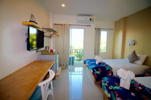 a room with two beds and a desk and a television at Green Apple Villa in Sattahip