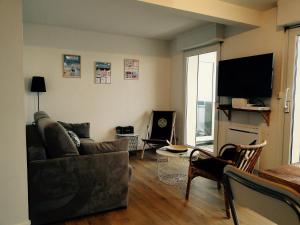 a living room with a couch and a television at les pieds dans l'eau in Wimereux