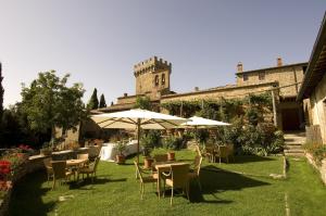 Castello Di Gargonza في مونتي سان سافينو: فناء به طاولات ومظلات أمام المبنى