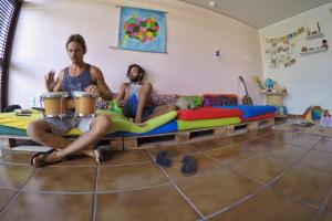 two men sitting on a couch playing drums at Slow Hostel - Hospedagem Criativa in João Pessoa