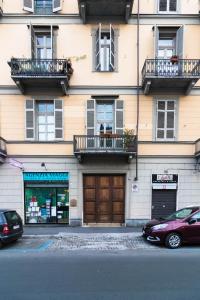 ein Gebäude mit zwei Balkonen und zwei Autos, die auf der Straße geparkt sind in der Unterkunft Mono Verde in Turin