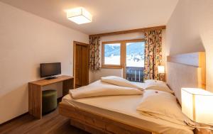 una camera da letto con un letto, una TV e una finestra di Ferienhaus Larinmos a Lermoos