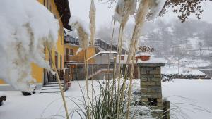 a snow covered yard with a yellow building with snow at Hotel Castello in Montjovet