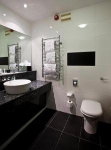 a bathroom with a white toilet and a sink at Quorn Country Hotel in Loughborough