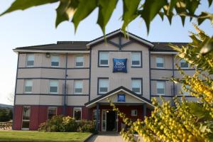 a large building with a blue sign on it at ibis budget Coutances in Coutances