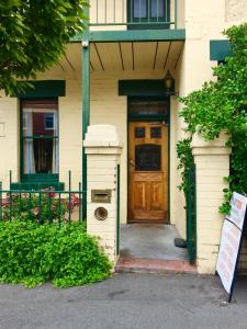 a front door of a house with a sign in front at Narrara Backpackers Hobart in Hobart