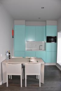 une cuisine avec des armoires bleues, une table et des chaises dans l'établissement Home Over The Sea, à Sesimbra