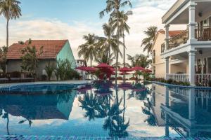 a swimming pool with red umbrellas and a building at Phuong Binh House in Phú Quốc