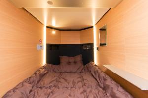 東京にあるRyoma Ikebukuroの木製の壁の小さな部屋の小さなベッド1台