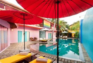 a pool with two red umbrellas next to a building at Dickman Resort "The Boutique Hotel" in Negombo