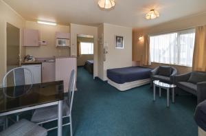 Una habitación de hotel con una cama y una cocina. en Geneva Motor Lodge, en Rotorua