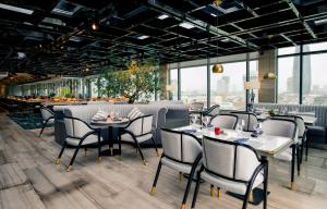 a restaurant with tables and chairs and windows at New Orient Hotel Da Nang in Danang