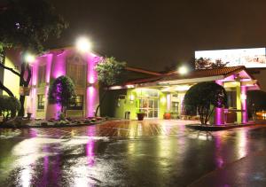 Stay Express Inn Dallas - Fair Park / Downtown في دالاس: مبنى به أضواء أرجوانية على شارع في الليل