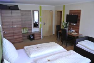 a hotel room with two beds and a desk at Hotel Daimerwirt in Moosinning