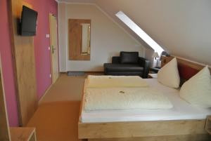 a bedroom with a bed and a chair in a room at Hotel Daimerwirt in Moosinning