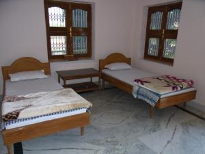 two beds in a room with two windows at Momotaro House in Bodh Gaya