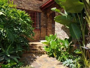 a brick house with a brick walkway in a garden at Kington Guest Suite in Pretoria