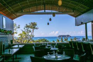 un restaurante con mesas y sillas y vistas al océano en Hotel San Bada Resort & Spa, en Manuel Antonio