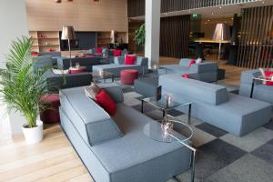 un hall avec des canapés bleus, des tables et des plantes dans l'établissement Hotel de la Source, à Francorchamps